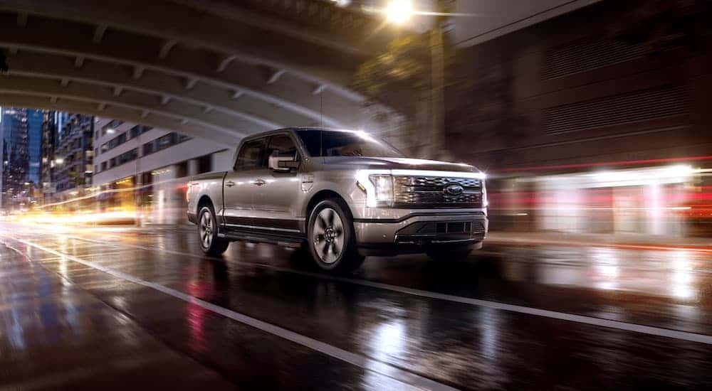 A silver 2025 Ford F-150 Lightning driving at night.