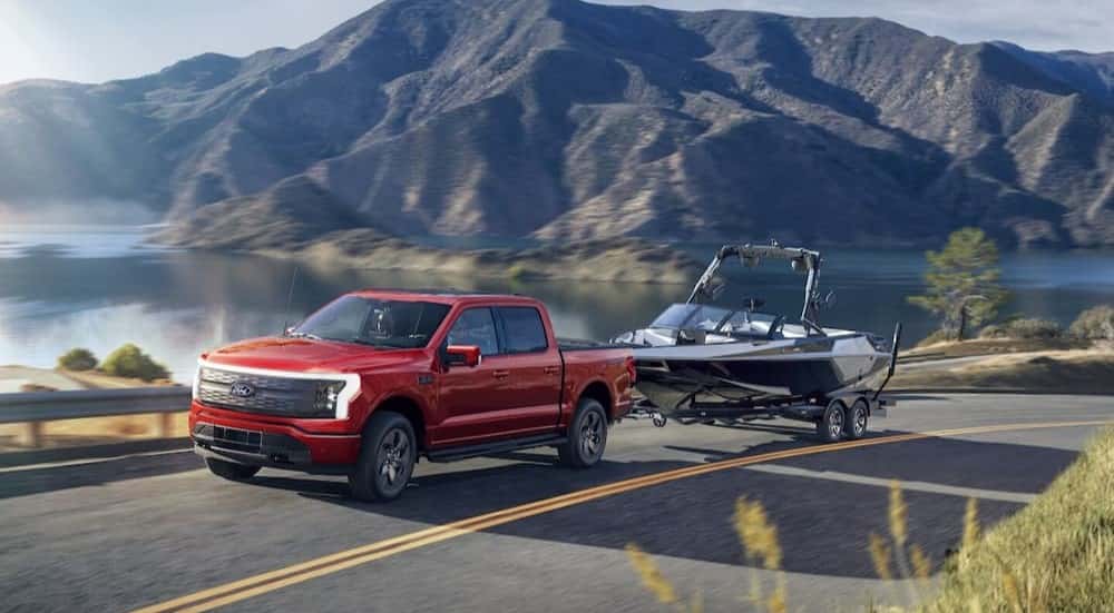 A red 2025 Ford F-150 Lightning for sale towing a boat.