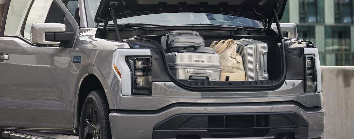 The open frunk of a silver 2024 Ford F-150 Lightning full of suitcases and travel bags.
