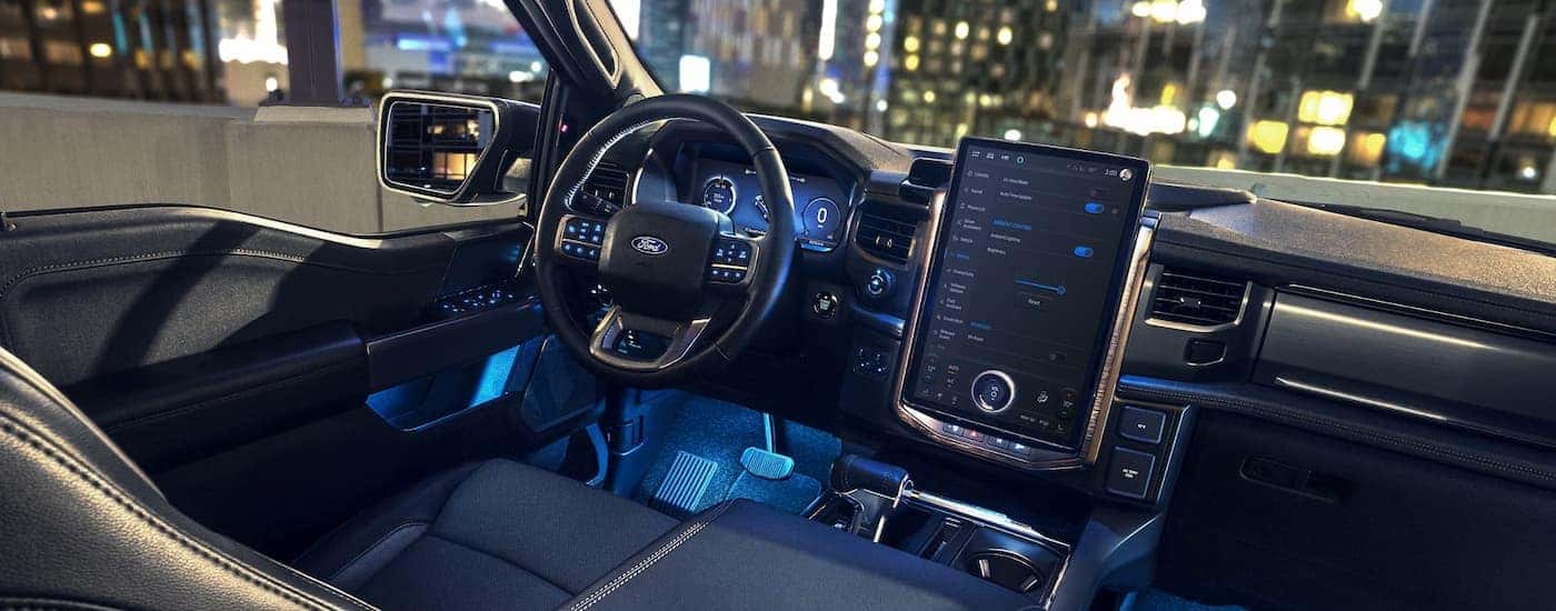 The black and blue illuminated dashboard interior of a 2025 Ford F-150 Lightning for sale.