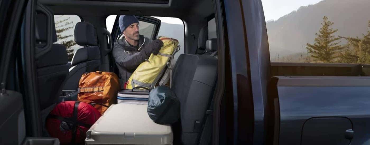 A man loading gear into the back of a blue 2024 Ford F-150 Platinum.