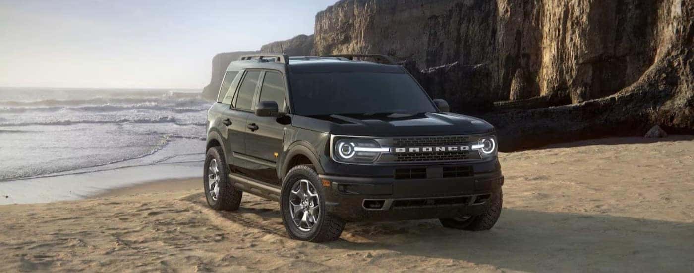 A black 2024 Ford Bronco Sport parked near an ocean.