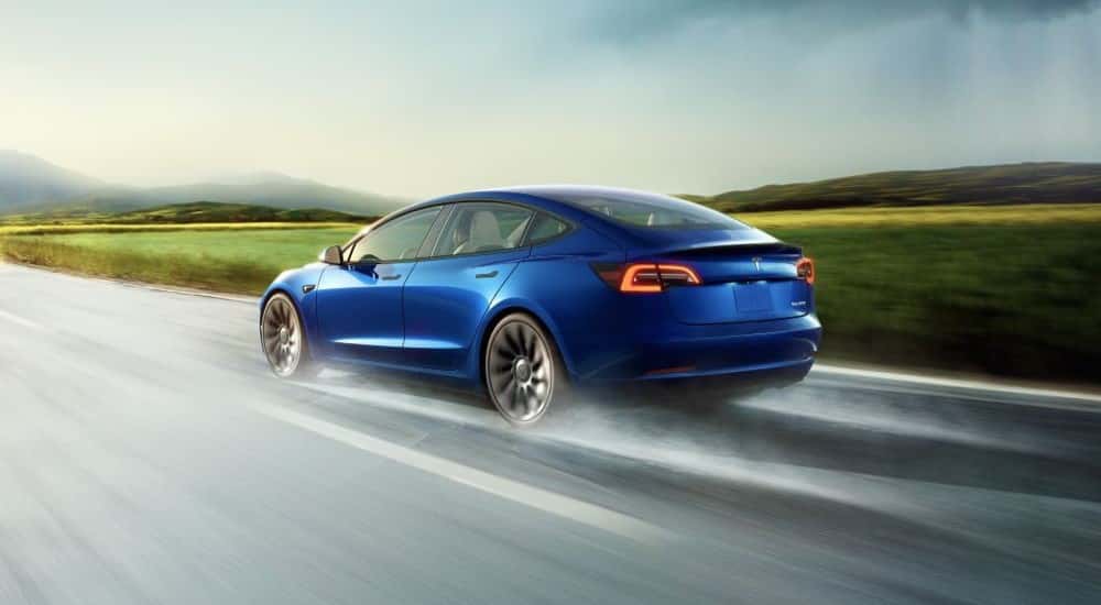 A used 2022 Tesla Model 3 driving on a wet road
