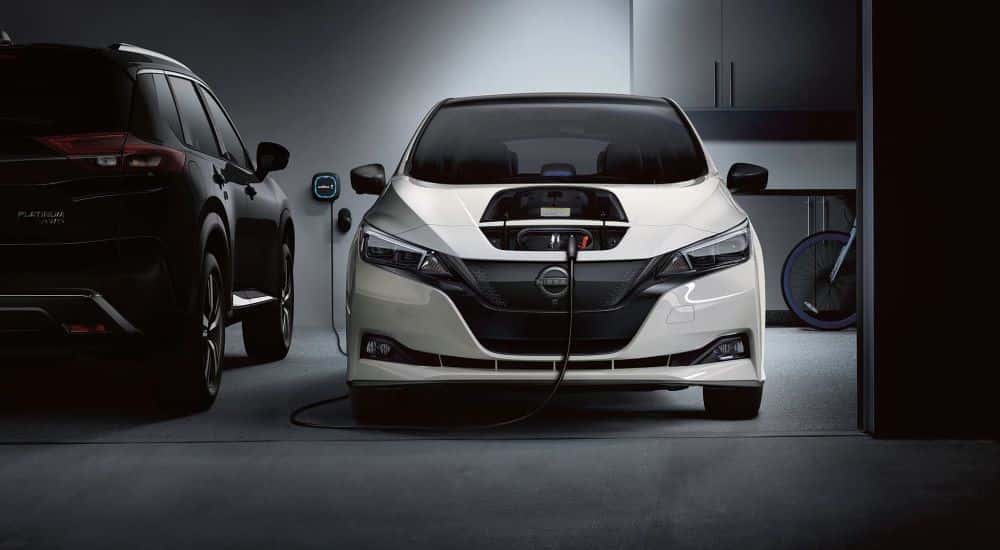 A white used Nissan LEAF charging in a garage