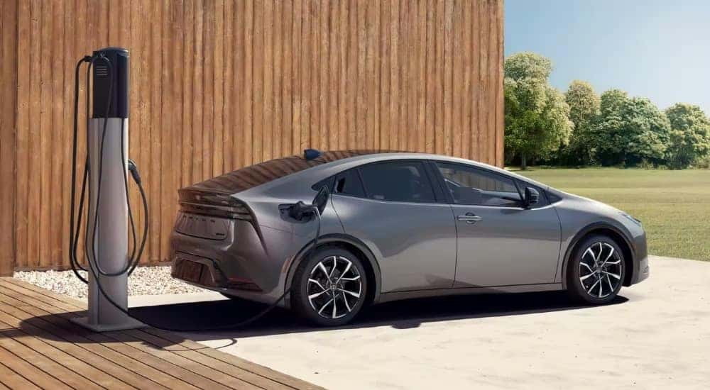 A silver 2023 Toyota Prius Prime XSE Premium charging on a driveway.