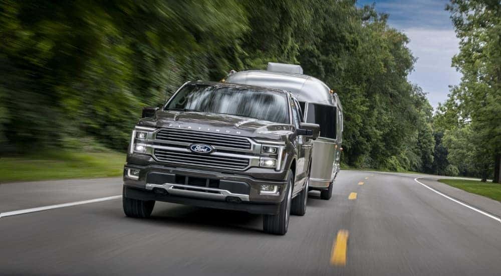 A grey 2024 Ford F-150 Platinum Hybrid towing an Airstream.
