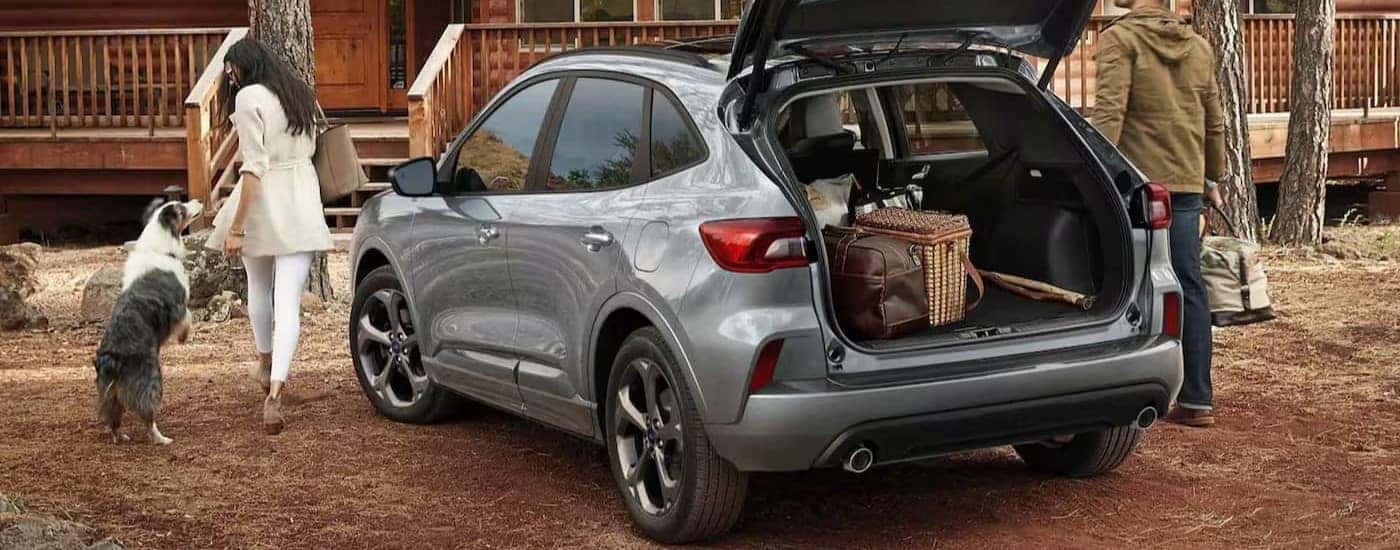 A silver 2023 Ford Escape Plug-In Hybrid parked near a cabin.