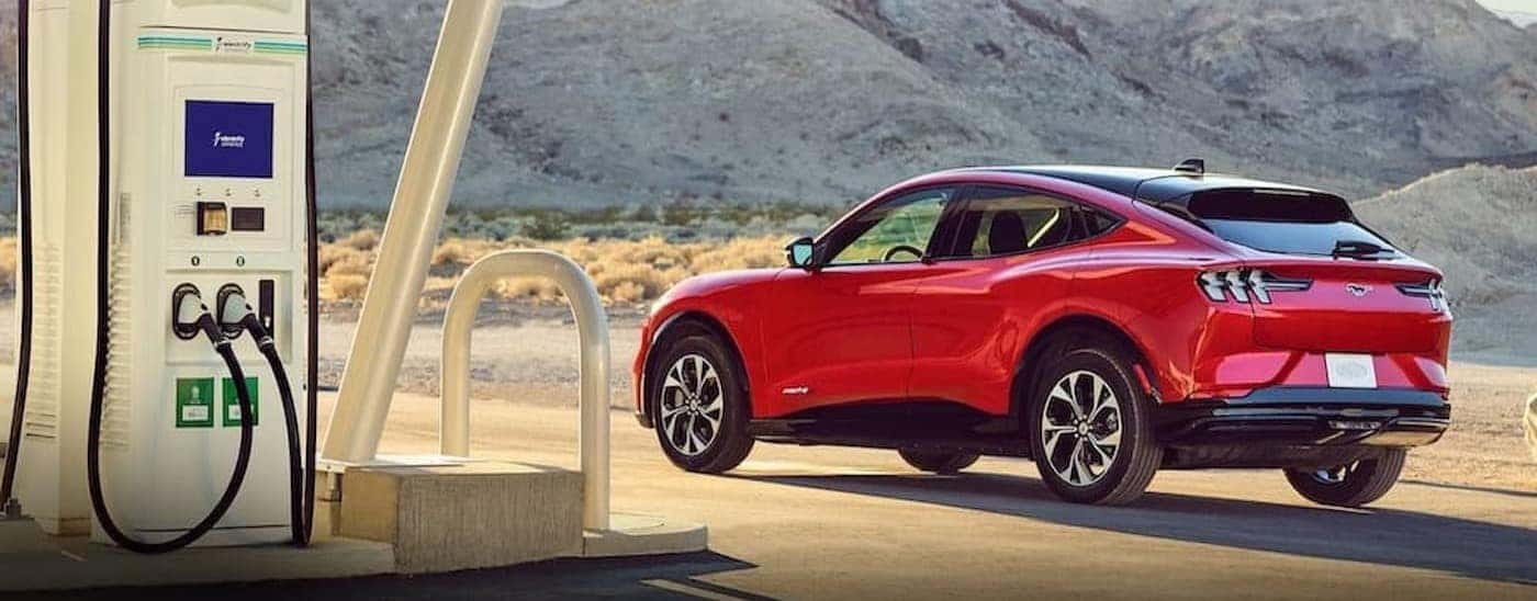 A red 2022 Ford Mustang Mach-E parked near a charge station.