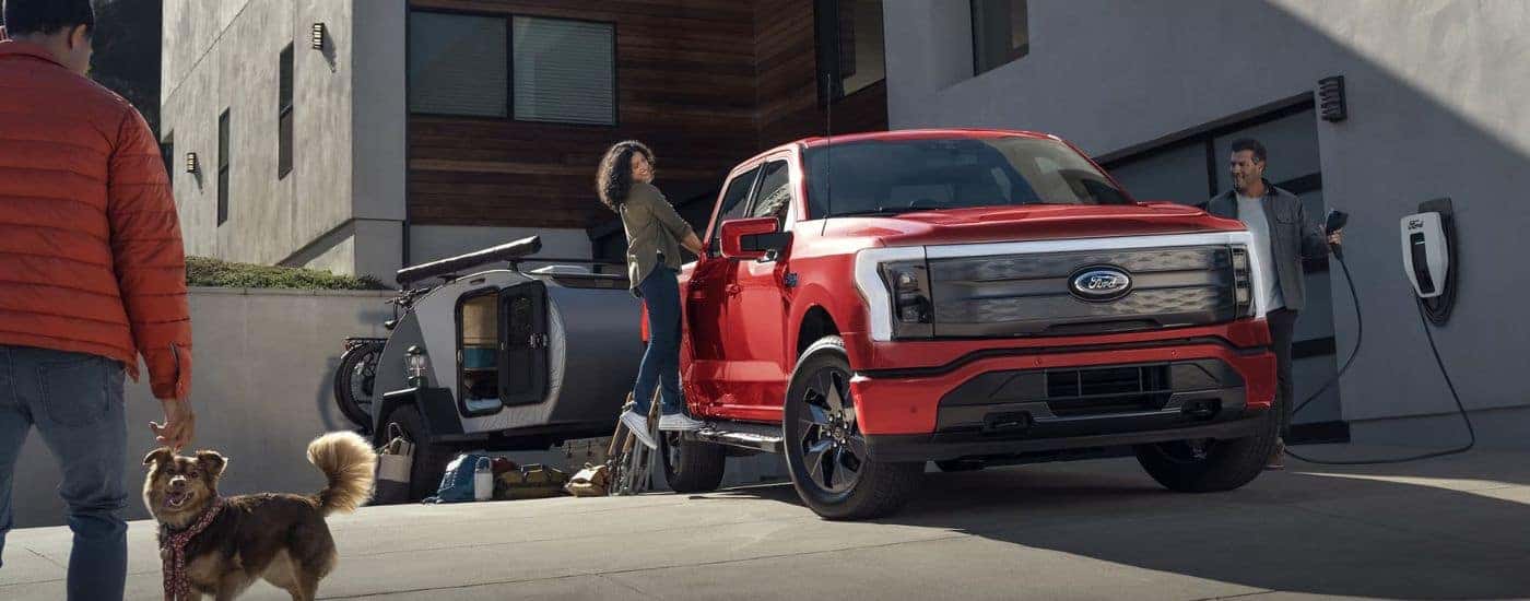 A red 2024 Ford F-150 Lightning is parked in a driveway.