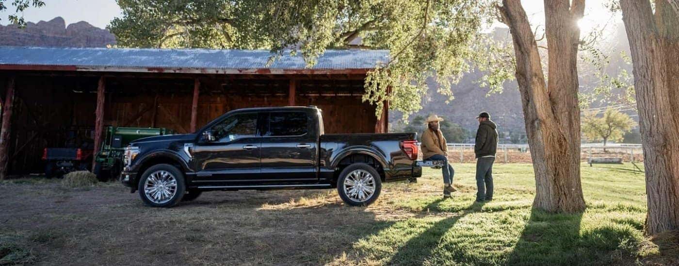 A black 2024 Ford F-150 for sale parked near a barn.