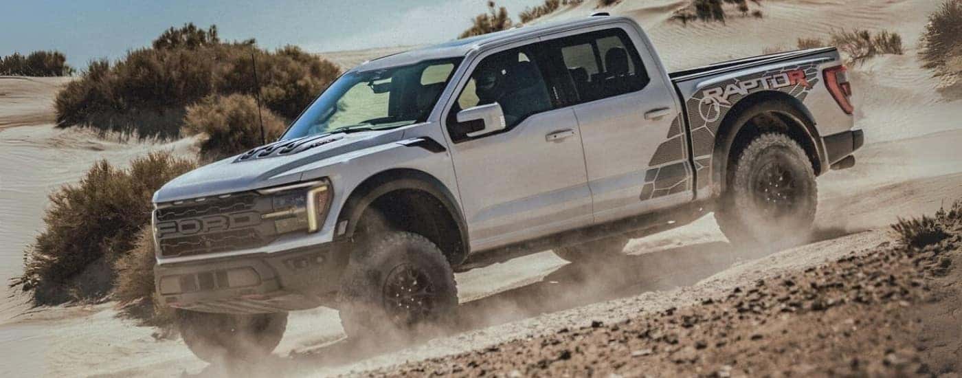 A grey 2024 Ford F-150 Raptor R driving on a dusty trail.