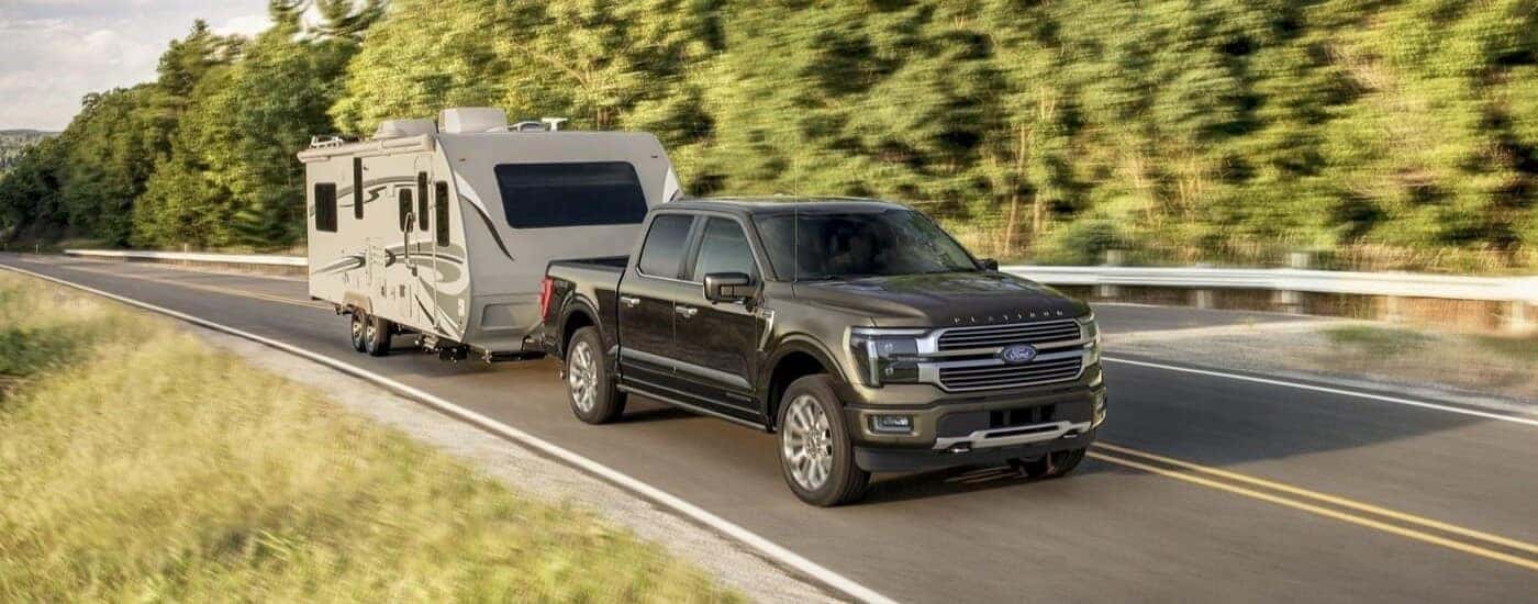 A grey 2024 Ford F-150 Platinum Plus towing a trailer.