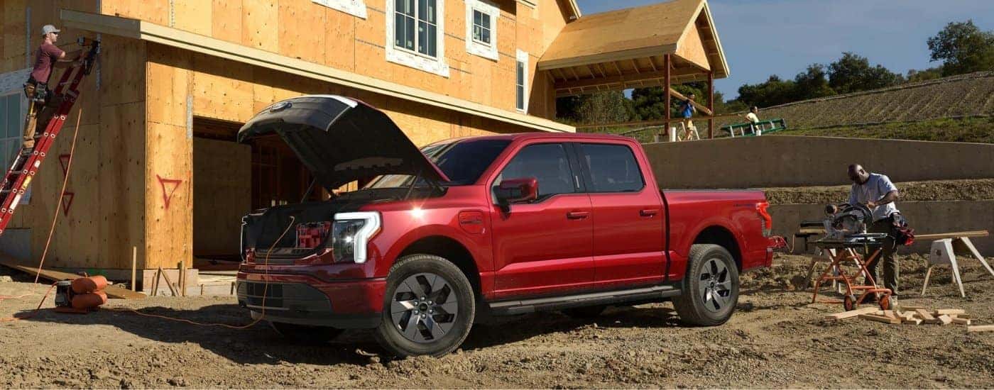 A red 2025 Ford F-150 Lightning for sale near Monterey at a construction site.
