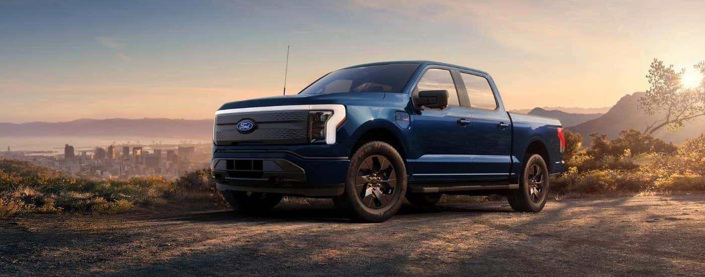 A blue 2022 Ford F-150 Lightning for sale in Santa Cruz parked at an overlook.