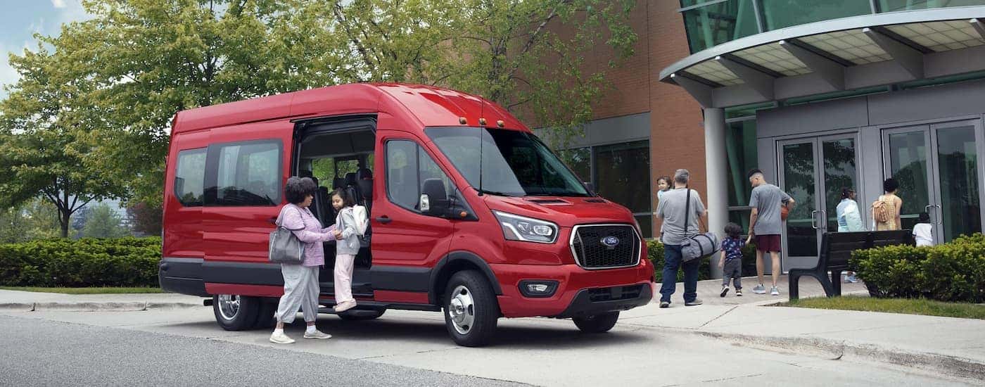 Red 2025 Ford Transit Van parked outside of a building