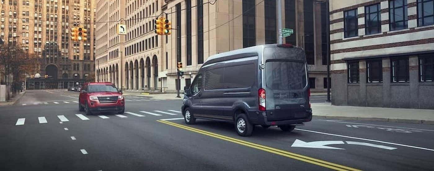 A gray 2024 Ford Transit driving in a city.