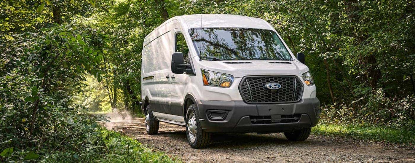 A white 2021 Ford Transit driving on a dirt road