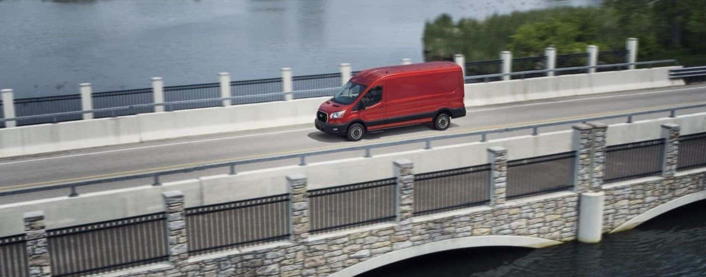 A red 2023 Ford Transit driving on a bridge