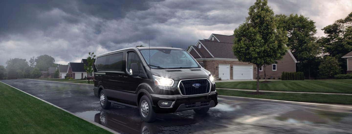 A black 2025 Ford Transit driving in the rain