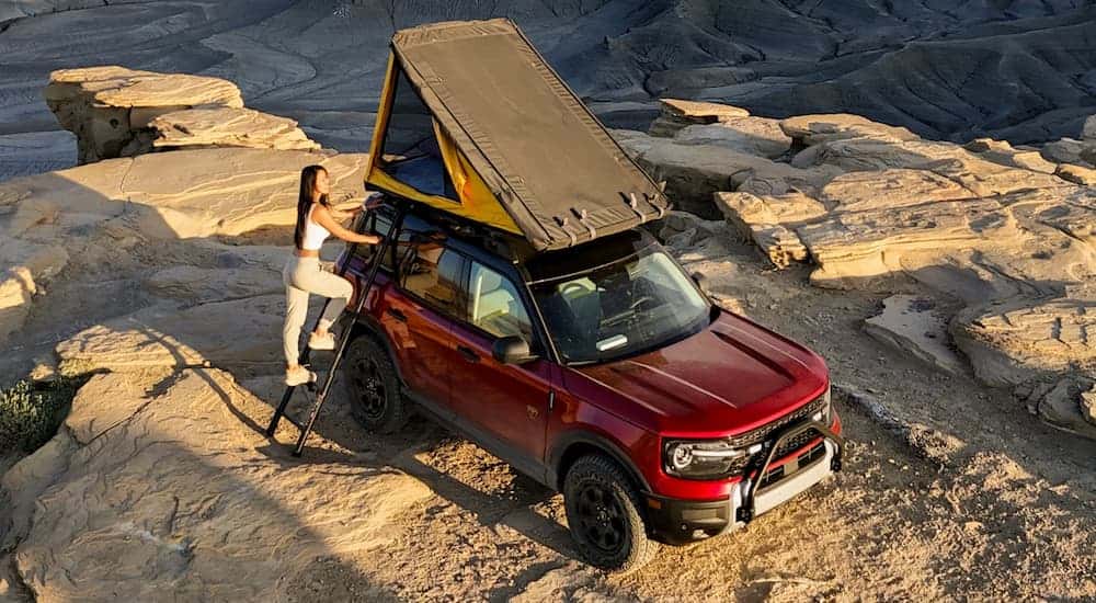 Red 2026 Ford Bronco Sport parked off-road with a roof top tent.