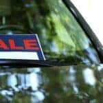 A car for sale parked outside with a sign in the windshield
