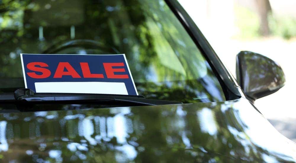 A car for sale parked outside with a sign in the windshield
