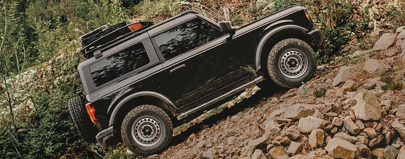 Black 2025 Ford Bronco driving off-road from the side at an angle.