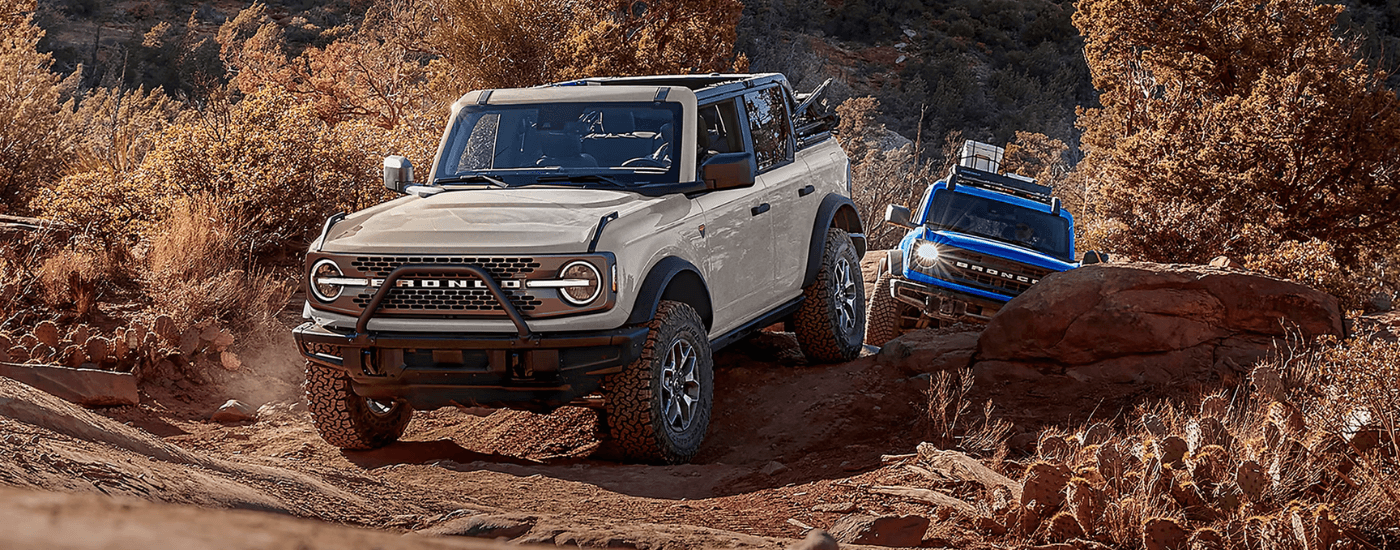 A white and a blue 2026 Ford Broncos driving off-road