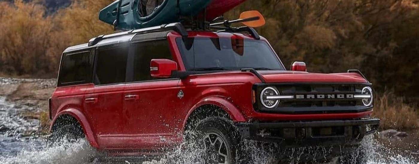 A red 2025 Ford Bronco Outer Banks off-roading in a stream