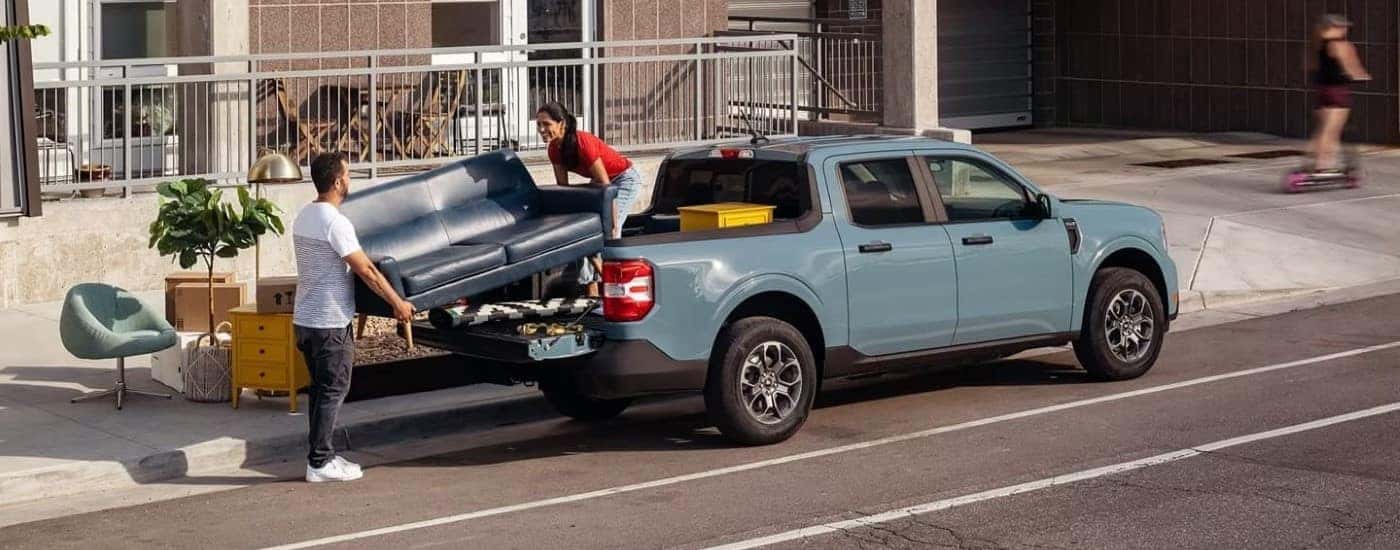 Blue 2022 Ford Maverick with people moving a couch