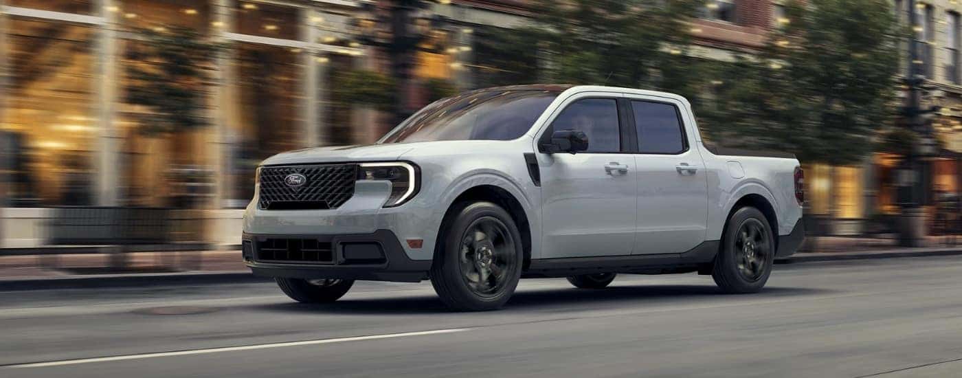White 2025 Ford Maverick driving down a city street.