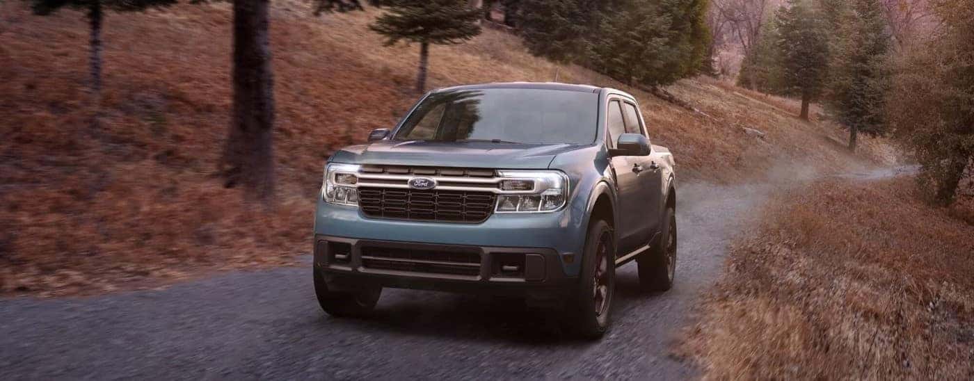 Blue 2023 Ford Maverick driving up a gravel driveway