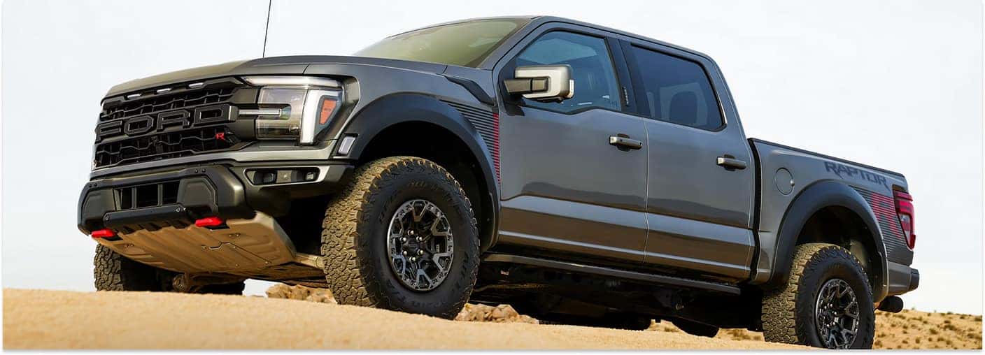 Gray 2026 Ford F-150 pickup truck parked on a dirt ridge, shown from a low front three-quarter view.