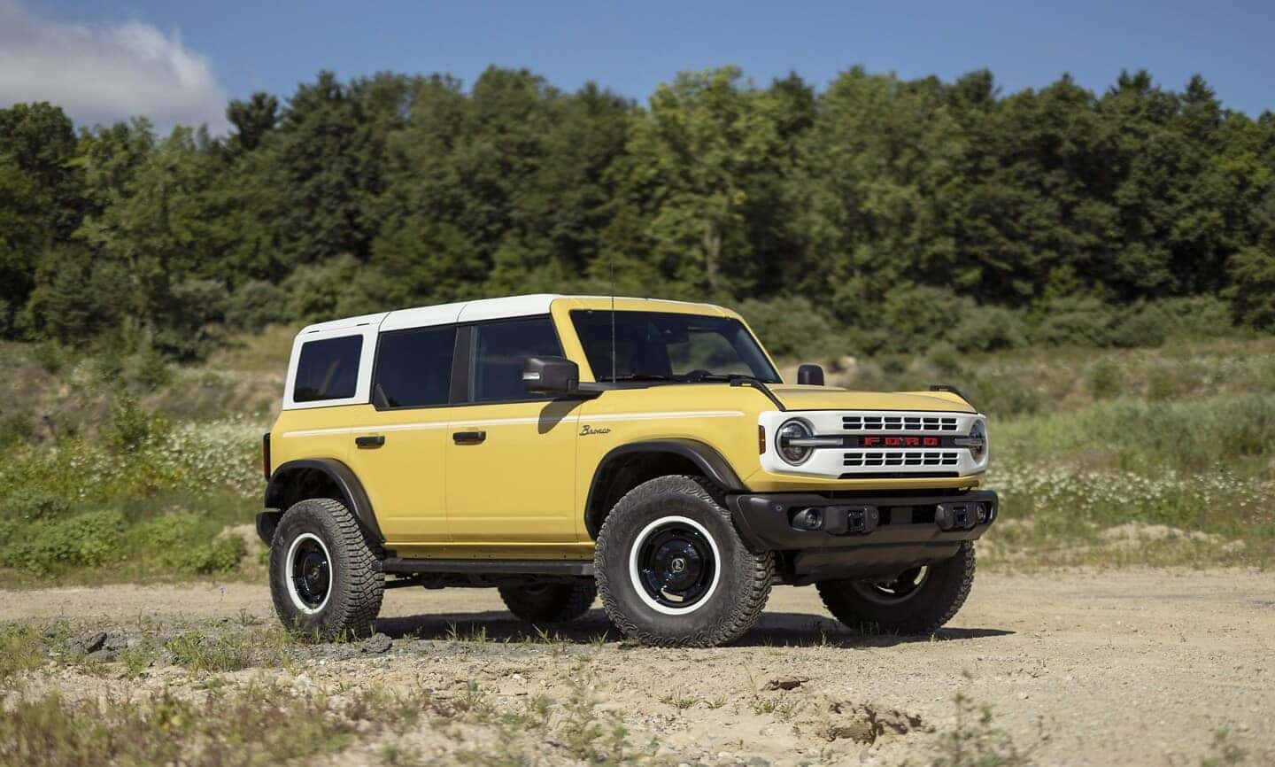 Yellow Ford Bronco Sport with white roof on a dirt road.