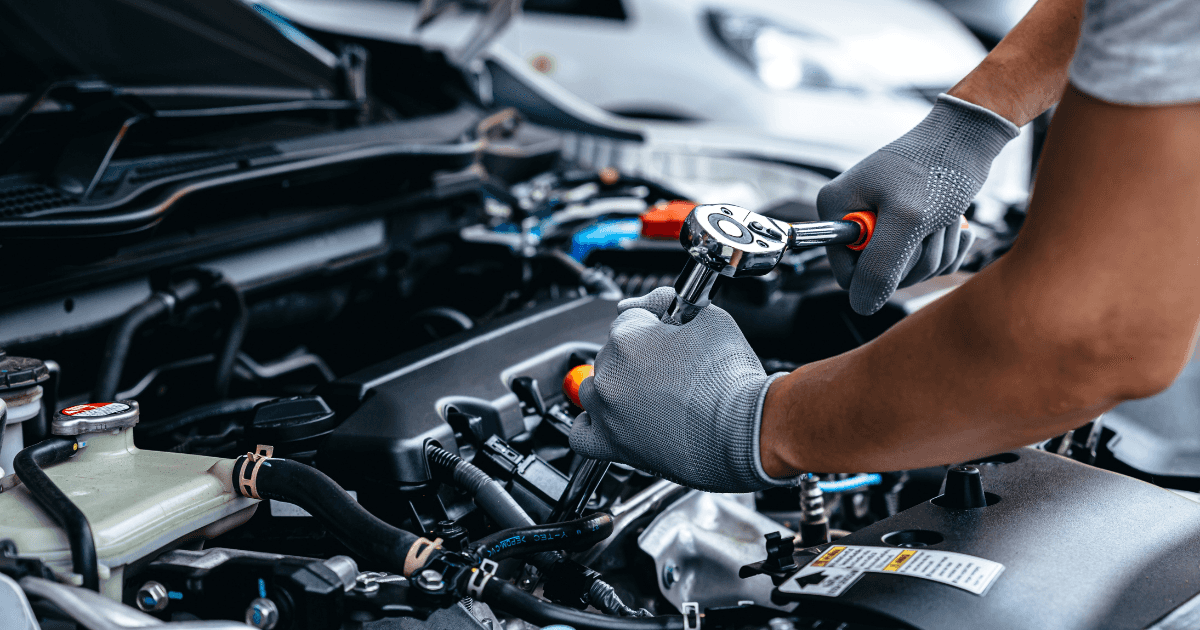 A mechanic repairing a vehicle using a wrench