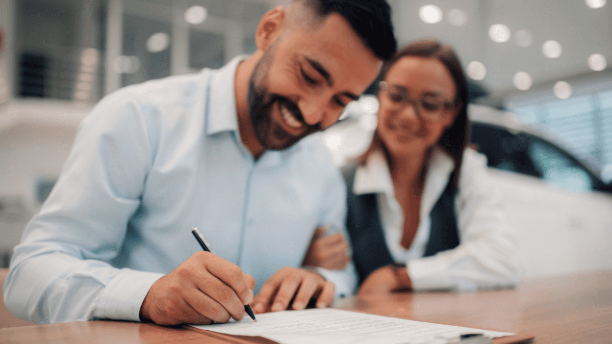 A happy couple signing a contract purchasing a new vehicle