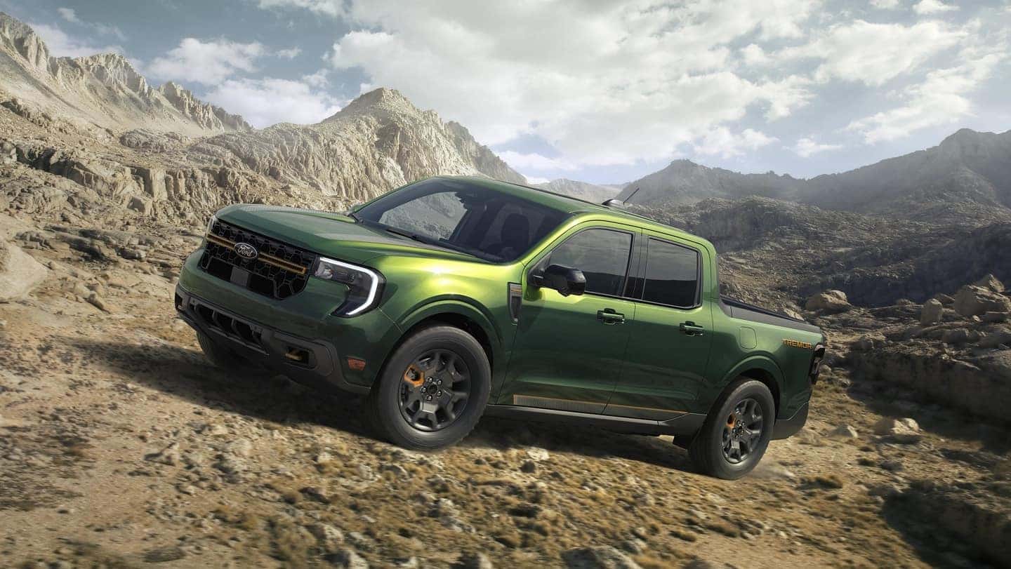 A green 2025 Ford Maverick driving over a rocky hill