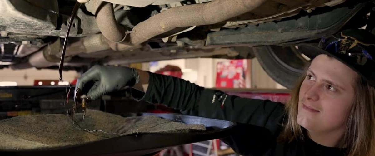 Technician performing oil change service draining fluids