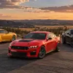 Three Mustangs at a mountain overlook: a yellow GT with the trunk badge readable, a red Dark Horse, and a black Dark Horse SC