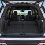A white Ford Explorer with the liftgate open, the cargo floor flat behind the second row, and the third row still upright