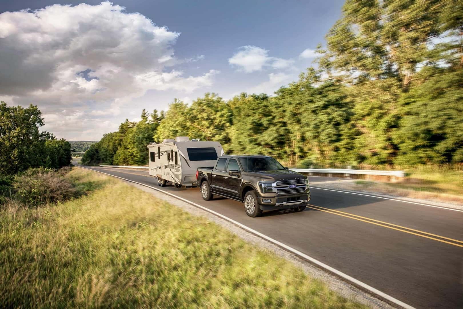 ford F-150 driving down scenic road with RV hitched to the back and motion blur
