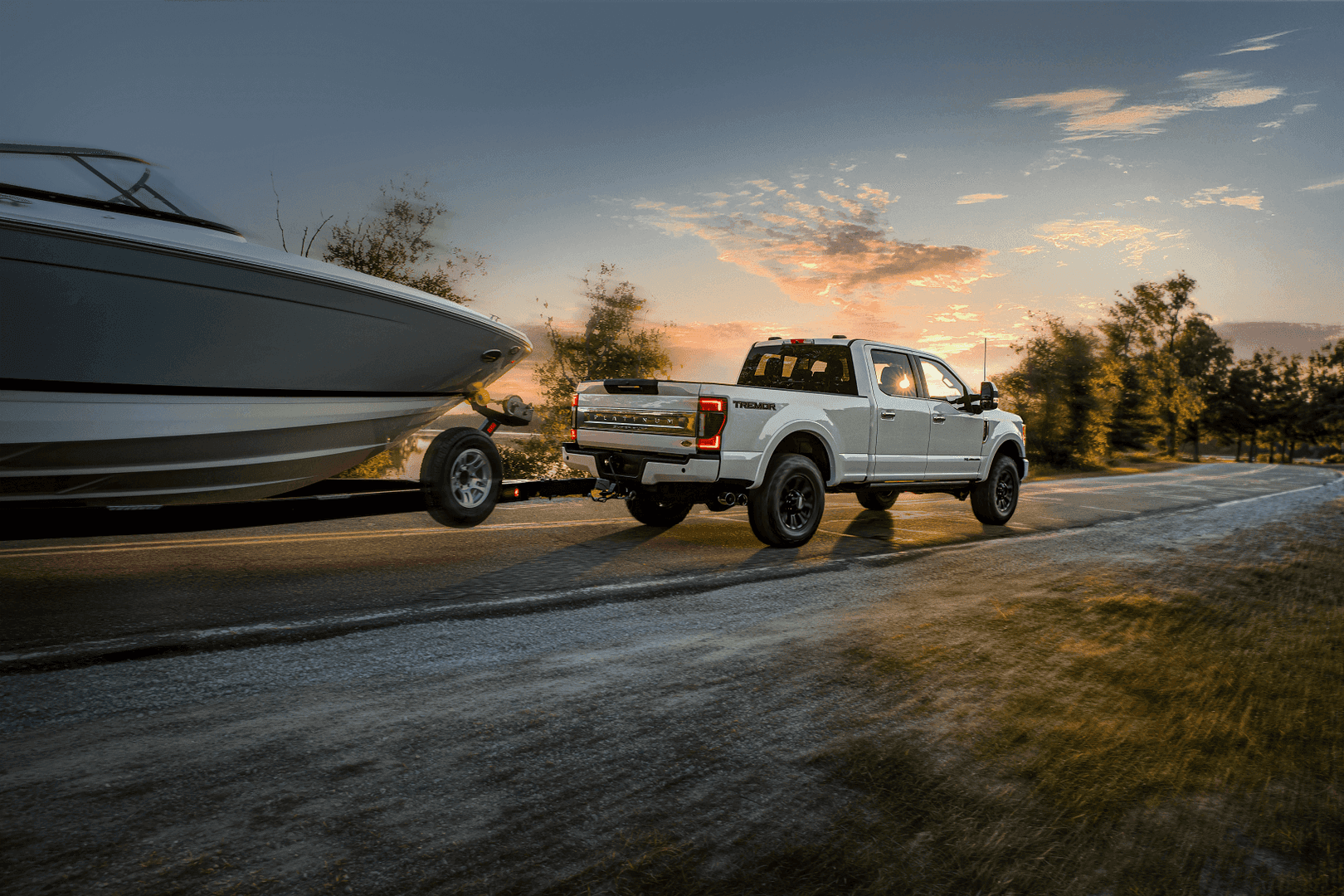 Ford Super Duty truck driving down scenic route towing boat with motion blur