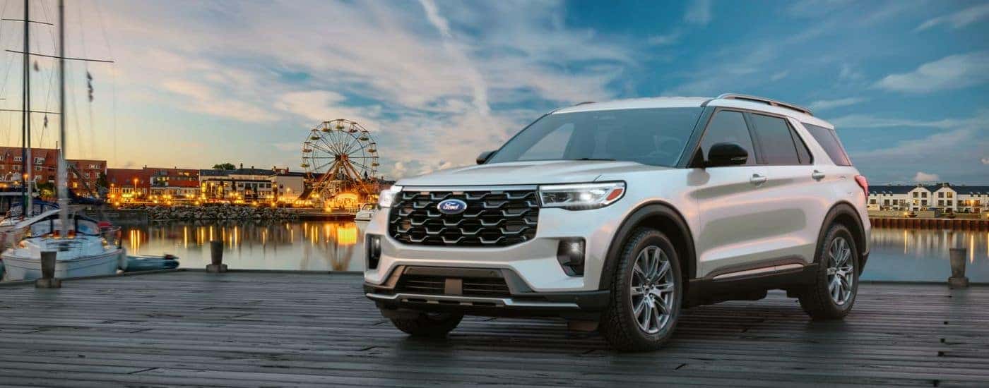 A silver 2026 Ford Explorer® SUV parked on a pier near an amusement park.