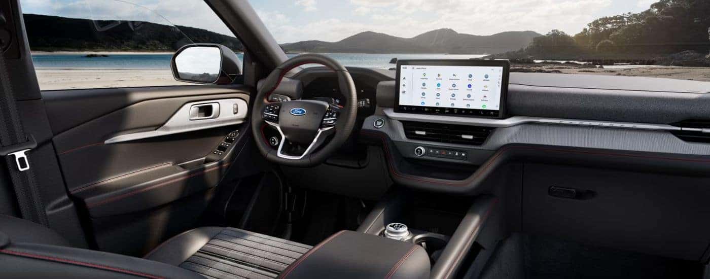 Interior view of a 2026 Ford Explorer infotainment display and steering wheel, parked on a beach.