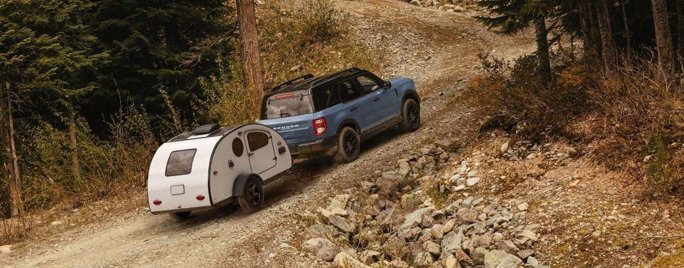 A blue 2026 Ford Bronco Sport towing a trailer offroad.