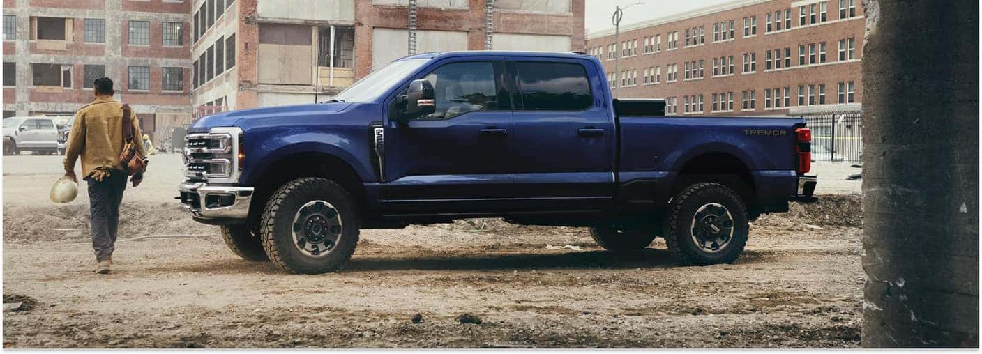Blue 2026 Ford F-250 Tremor pickup truck in profile view at a construction site.