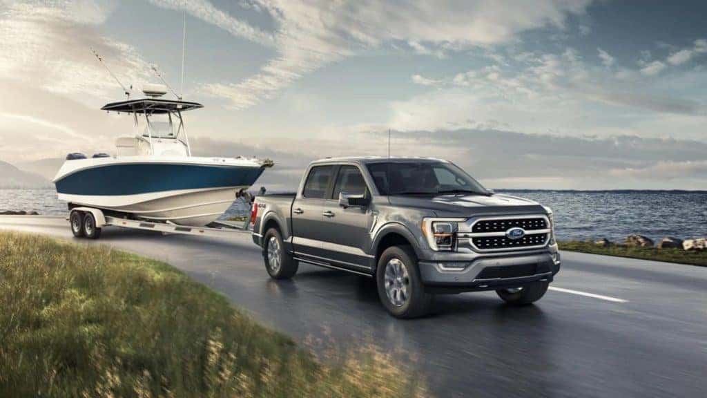 2022 gray ford f150 in motion towing a boat on the road