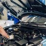 a service technician opens the hood of a vehicle to inspect and exam vehicle maintenance