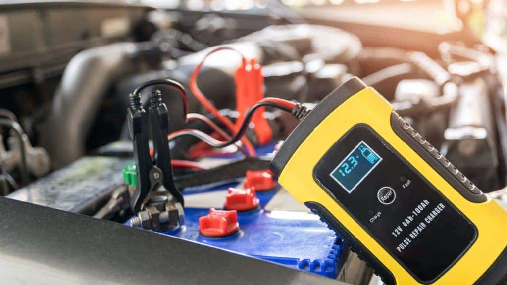 a car battery being tested in a vehicle with a battery tester showing the voltage
