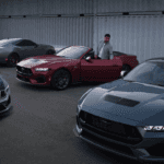 Two friends look over the 2024 Mustang in different colors on a highway.